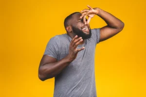afro american man isolated against yellow background smelling something stinky disgusting intolerable smell holding breath 185889951
