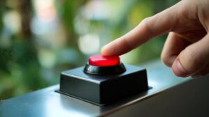finger poised over a bright red button a hand with a finger is about to press a large red button in a colorful environment filled with greenery photo