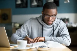 focused millennial african student making notes studying i american glasses writing down information book cafe 117587039