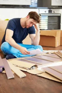 frustrated man putting together self assembly furniture close up whilst sitting floor 34165023