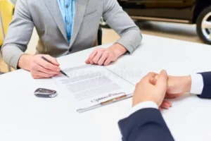 man signing papers to buy car close up young handsome men reading purchase contract sitting desk dealership shop buying 108620562
