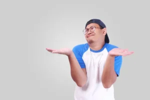shrug shoulder up showing i don t know gesture photo image portrait cute funny young asian man unhappy face looking both 104697328
