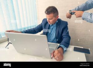 keep track of time man point at clock work time or working hours time management office life time for work being late at work boss scolds emplo 2K6FE37