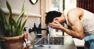 man washing face water splash bathroom grooming skincare morning routine male person cleaning rinse tap 421439500