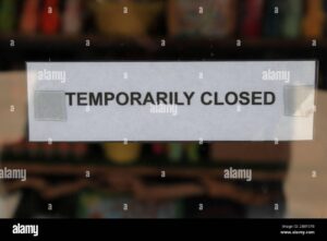 temporarily closed sign taped to the door of a business during the covid 19 pandemic 2BBY37B